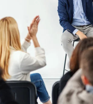 Woman clapping while listening to a speaker